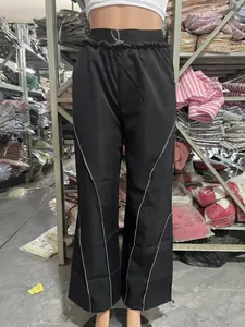 Close-up of black high-waisted pants with contrast stitching and adjustable drawstring hem