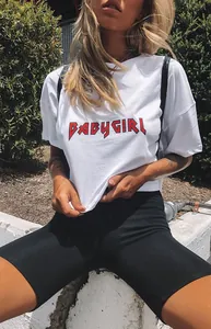Fit woman wearing high-waist black biker shorts and white babygirl graphic T-shirt outdoors