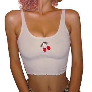 Close-up of white ribbed crop tank top with detailed cherry embroidery on the chest.