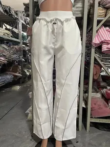 Detailed view of white high-waisted drawstring pants with silver reflective piping