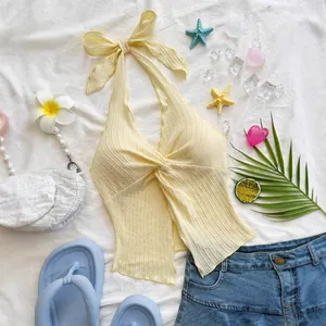 Detailed view of yellow ribbed halter neck crop top with front twist and tie bow.