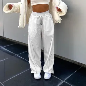 Detail view of white high-waisted drawstring pants with toggle and reflective piping