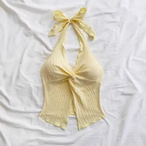 Close-up view of a yellow halter top featuring a twisted front and ribbed fabric