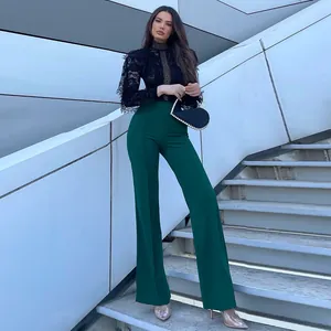 Elegant emerald green high-waisted flared trousers shown on a model on modern stairs.
