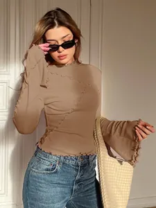 Vista dettagliata delle cuciture ondulate asimmetriche su top beige con maniche a campana