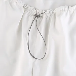Close-up of adjustable elastic waist with drawstring and toggle on white trousers