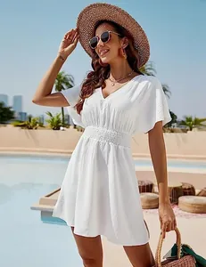 Detailed view of a white V-neck beach dress with smocked waist and flutter sleeves