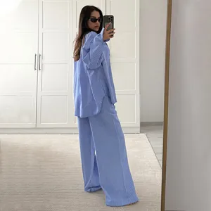 Selfie allo specchio di un set donna camicia a righe blu e bianche e pantaloni larghi.