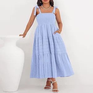 Détail d'une robe bleu clair avec bustier smocké et bretelles à nouer