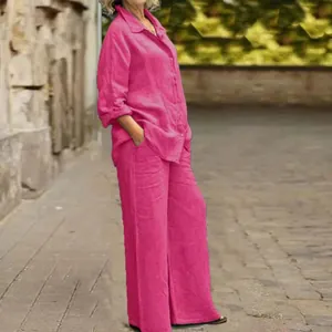 Modella indossa camicia magenta a maniche lunghe e pantaloni larghi coordinati all'aperto.