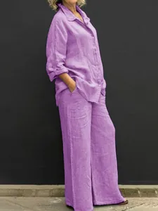 Vista dettagliata di un completo casual in lino viola con camicia a bottoni e pantaloni larghi.