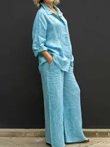 Vista laterale di una donna che indossa camicia di lino celeste e pantaloni a gamba larga