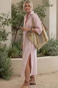 Full view of elegant women's pink striped shirt dress with side slits and tote bag