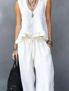 Lifestyle view of white linen sleeveless ruffle top and wide-leg trousers set