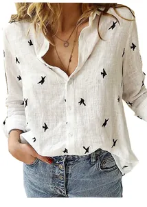 Close-up of women's loose white linen shirt featuring black bird print and buttons