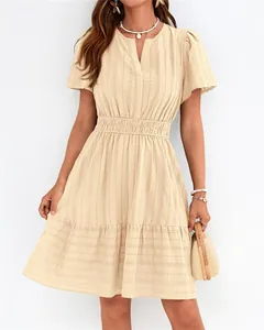 Détail d'une robe beige à col en V, manches bouffantes et ourlet à volants