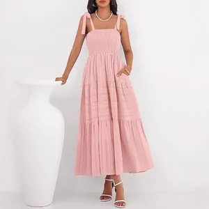 Robe longue rose à volants sans manches avec corsage smocké et bretelles à nouer.