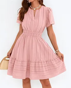 Détail d'une robe rose à col en V avec manches bouffantes et ourlet à volants.