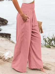 Detail of pink smocked high waist wide leg cotton casual trousers for women on beach