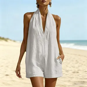 Vista detallada de un mono blanco con cuello halter y escote en V en un modelo en la playa soleada