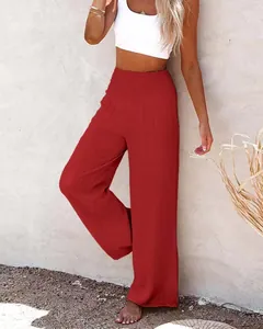 Full length view of women's red wide-leg cotton pants styled with a white crop top against wall