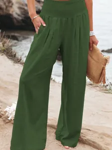 Detail view of women's green high-waisted smocked wide-leg trousers in soft cotton.