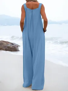 Detailed back view of a breezy light blue sleeveless wide-leg summer jumpsuit on a beach.
