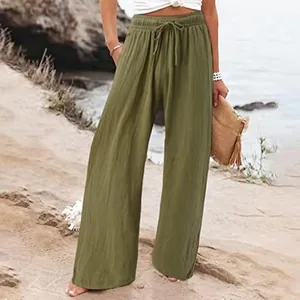 Détail du pantalon large en coton et lin vert olive pour femme sur une plage ensoleillée