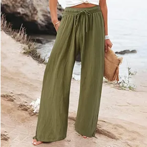 Vue détaillée du pantalon large en lin vert olive dans un cadre de plage relax