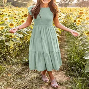 Detailed shot of a sage green tiered smocked midi dress in a sunny sunflower field