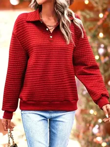 Close-up of red quilted waffle knit sweatshirt featuring a polo collar and button detail.