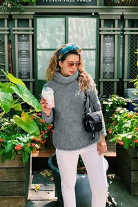 Κομψό γκρι φούτερ από fleece sherpa με ζιβάγκο φορεμένο από μοντέλο σε κήπο καφέ