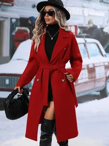 Eleganter roter zweireihiger Wollmantel mit Taillenband an einem Model im Winterdorf