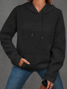Detalle de sudadera negra con capucha para mujer con textura de letras en relieve 3D