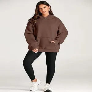 Full body detail of a women's brown oversized hoodie paired with black sports leggings