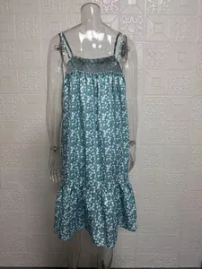 Detail of a turquoise floral camisole dress with ruffled hem on a transparent mannequin.