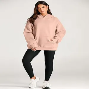 Full body view of a woman wearing an oversized nude pink hoodie with black leggings