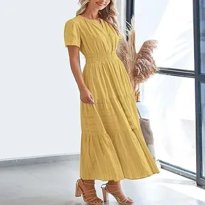 Stylish woman wearing a yellow V-neck tiered maxi dress with puff sleeves in indoor setting.