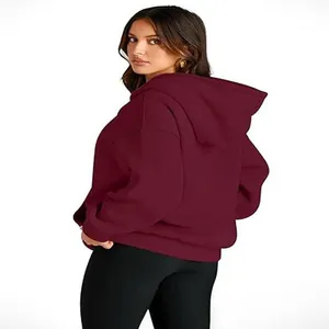 Back view of a woman wearing a burgundy oversized hooded sweatshirt and black leggings.