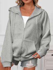 Close-up of gray waffle-knit texture and zipper detail on a casual women's hooded jacket.