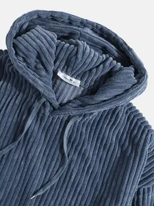 Close-up detail of blue corduroy hoodie fabric texture with drawstring hood and neck label