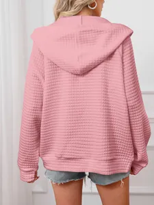 Back view of women's pink waffle knit hooded sweatshirt showing textured fabric details