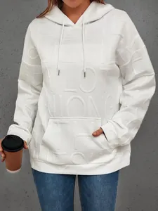 Detalle de sudadera blanca oversize con capucha y letras en relieve 3D para mujer
