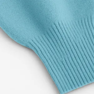 Detailaufnahme der Rippbündchen und des weichen Strickstoffs eines blauen Pullovers