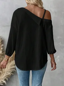 Detail of black textured off-shoulder shirt with asymmetrical collar and 3/4 sleeves.