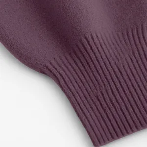 Makrodetail eines pflaumenfarbenen Strickpullovers mit weichem Stoff und Rippbündchen