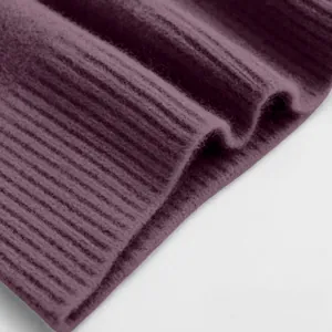 Detailaufnahme der weichen lila Rippstrick-Struktur eines warmen Winterpullovers