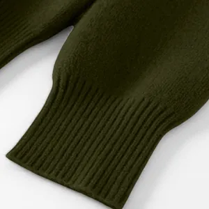 Detailaufnahme der gerippten Manschette eines lockeren dunkelgrünen Strickpullovers