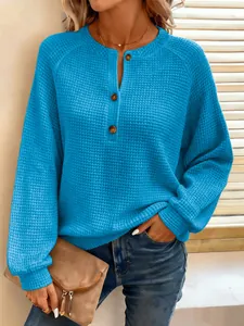 Detailopname van een helderblauwe wafelgebreide trui met een henley-knoopsluiting.