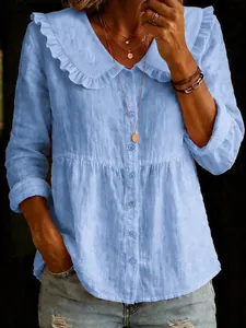 Close-up of light blue cotton linen blouse featuring ruffled Peter Pan collar and buttons